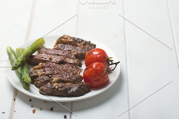 Grilled beef steak on a white plate and white background