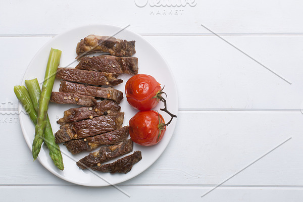 Grilled beef steak on a white plate and white background, flat lay and copy space