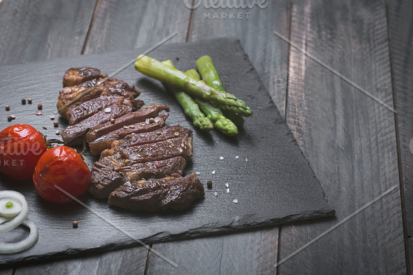 Grilled beef steak with vegetables on a black background