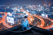Asian businessman using phone and laptop on rooftop with social connection lines in smart city at night