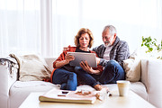 Senior couple with tablet relaxing at home.