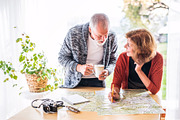 Senior couple with map at home, making plans.