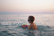 Child taking ball to water and then floating on it in the sea