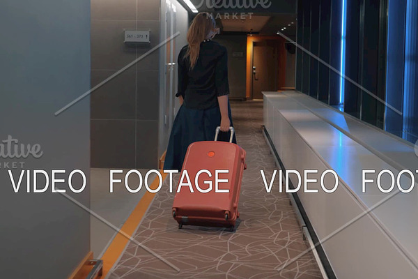 Woman with trolley case in the hotel hallway