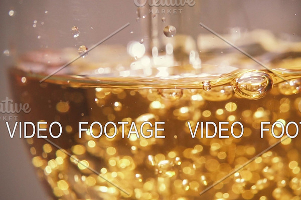 Slow motion in a glass to pour a yellow drink with bubbles