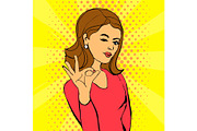 Wink pop art face. Beautiful woman with dark hair shows OK sign. Vector background in retro comic style with dotts.