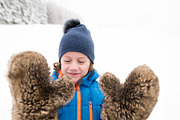 Cute boy wearing big furry gloves outside in winter nature
