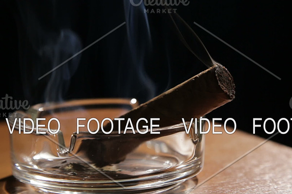 Smoking cigar in an ashtray.