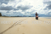 Man driving a motorcycle on beach.