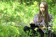 Girl uses a tablet in the woods.