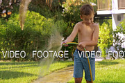 Child watering lawn with hose